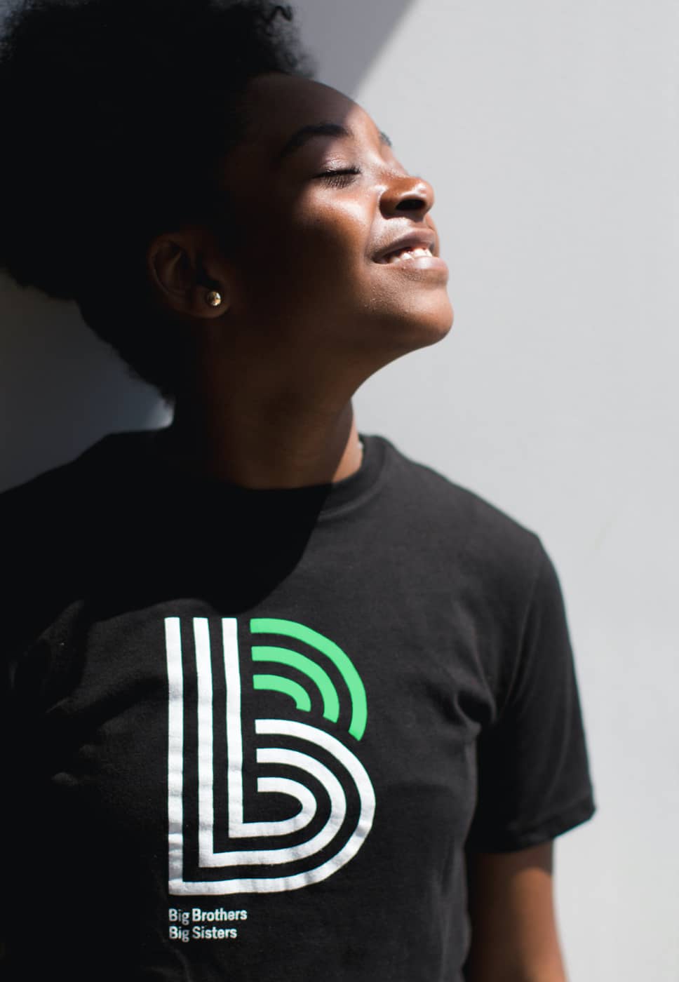 A smiling child wearing a Big Brother Big Sisters shirt.