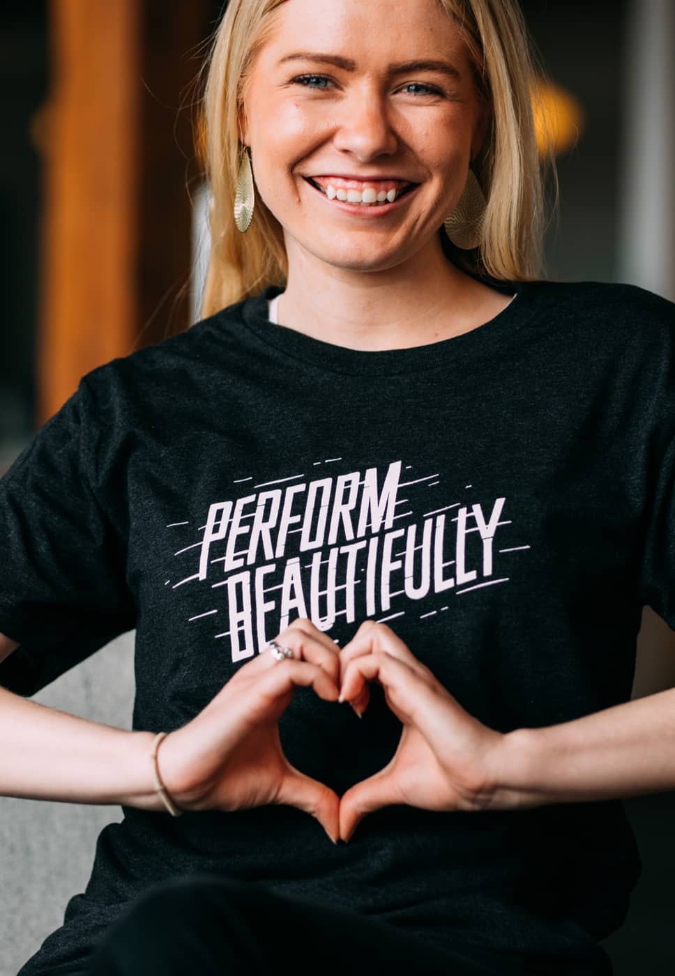 Our Talent Coordinator Maggie smiling wide and making a heart shape with her hands.